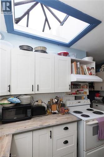 Kitchen featuring white shaker-style cabinetry, wood-finish countertops, a white subway tile backsplash, and a large skylight - 707 E King Street E, Cambridge, ON 