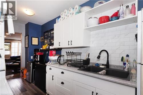 White cabinetry with black hardware, stone-finish countertops, black sink, and a white subway tile backsplash - 707 E King Street E, Cambridge, ON 