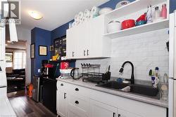 White cabinetry with black hardware, stone-finish countertops, black sink, and a white subway tile backsplash - 