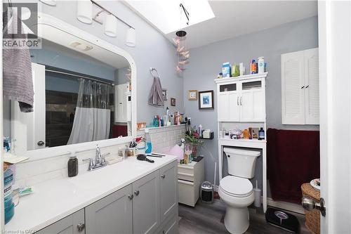 Vanity with an integrated sink, track lighting, wood-finish flooring, white wall cabinetry, and a skylight - 707 E King Street E, Cambridge, ON 