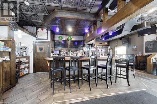 Detailed patterned ceiling, wood-finish flooring, built-in wooden bar, integrated overhead lighting, and multiple mounted screens - 707 E King Street E, Cambridge, ON 