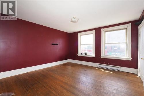 Hardwood flooring, two windows, baseboard heating, ceiling-mounted light fixture, and a built-in wall shelf - 707 E King Street E, Cambridge, ON 
