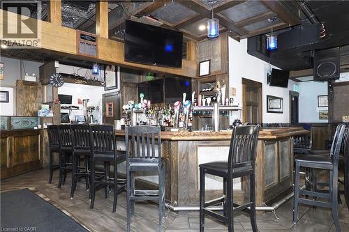Expansive bar area featuring a wood-finish bar top, integrated tap system, and decorative ceiling panels - 707 E King Street E, Cambridge, ON 
