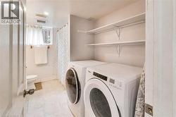 Laundry area featuring a stacked washer and dryer, open shelving, and tile flooring - 
