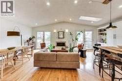 Hardwood flooring throughout, vaulted ceiling, recessed lighting, white brick fireplace, and built-in white cabinetry - 