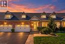 Brick facade residence featuring multiple dormer windows, a two-car garage with arched window inserts, a stone walkway, and established landscaping - 31 Book Road Unit# 44, Grimsby, ON 