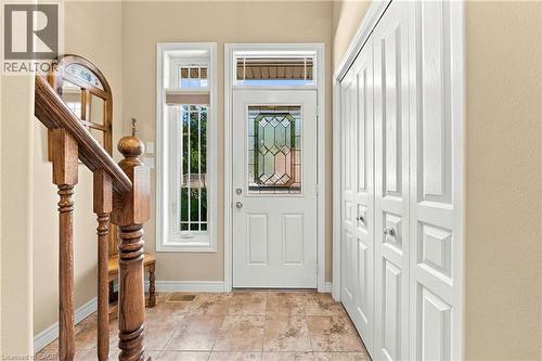Entryway featuring ceramic tile flooring, a white paneled door with leaded glass, side windows with grilles, and bi-fold closet doors - 31 Book Road Unit# 44, Grimsby, ON 