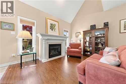 Varnished wood-finish flooring, vaulted ceiling, and a fireplace with a white mantel and surround - 31 Book Road Unit# 44, Grimsby, ON 