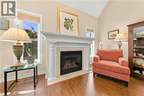 Wood-finish flooring, fireplace with a mantel, vaulted ceiling, and built-in display cabinetry - 31 Book Road Unit# 44, Grimsby, ON 