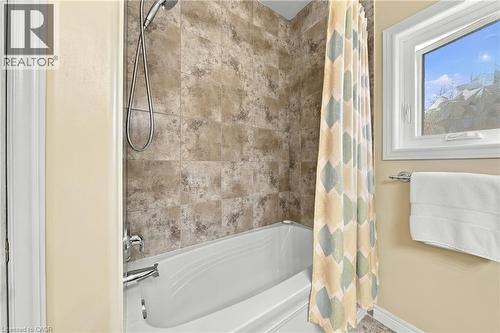 Bathtub with a shower fixture, tile surround, and an adjacent window - 31 Book Road Unit# 44, Grimsby, ON 