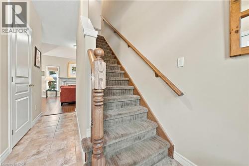 Staircase featuring wood handrail and newel post, carpeted steps, and neutral wall tones - 31 Book Road Unit# 44, Grimsby, ON 