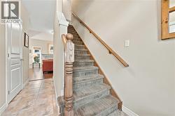 Staircase featuring wood handrail and newel post, carpeted steps, and neutral wall tones - 