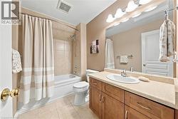 Bathroom featuring a vanity with an oval sink, wall-mounted light fixture, full-width mirror, a tub/shower combination with tile surround, and tile flooring - 