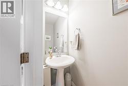 Pedestal sink with chrome fixtures, wall-mounted mirror, and overhead vanity lighting - 