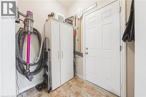 White paneled door with polished hardware, built-in storage cabinetry, and patterned floor tiles - 31 Book Road Unit# 44, Grimsby, ON 