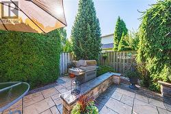 Patio area featuring stone tile hardscaping, built-in stone wall, privacy fencing, and mature evergreen plantings - 
