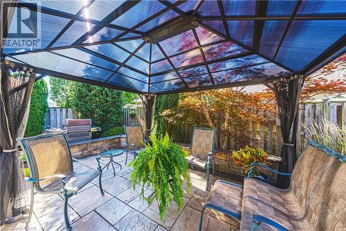 Patio with a metal gazebo featuring a translucent roof, stone paver flooring, and a stone-clad retaining wall - 31 Book Road Unit# 44, Grimsby, ON 