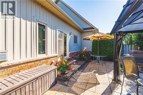 Light-colored vertical siding with brick detailing, stamped concrete patio, and mature landscaping - 31 Book Road Unit# 44, Grimsby, ON 