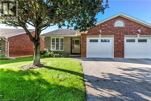 Brick and stone exterior with a single garage, manicured lawn, and a paved driveway - 150 Oak Street Unit# 27, Simcoe, ON 