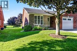 Brick and stone-finish exterior featuring a single garage, front entry, and mature landscaping - 