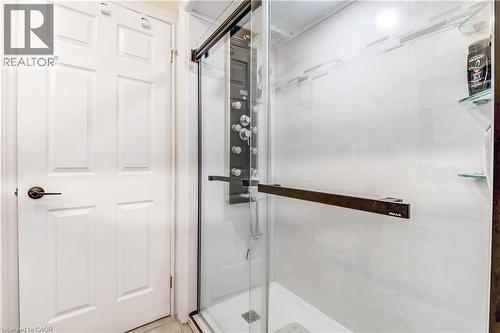 Glass-enclosed shower with a multi-function jet system shower panel, contemporary tile surround, and integrated glass shelving - 150 Oak Street Unit# 27, Simcoe, ON 