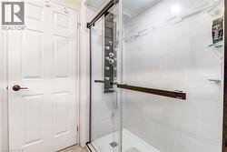 Glass-enclosed shower with a multi-function jet system shower panel, contemporary tile surround, and integrated glass shelving - 