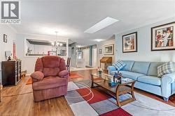 Living area featuring wood-finish flooring, a skylight, and crown molding - 