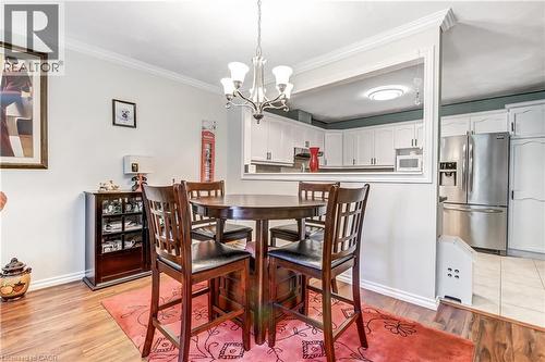 Wood-finish flooring, crown molding, and a chandelier illuminate the dining area - 150 Oak Street Unit# 27, Simcoe, ON 