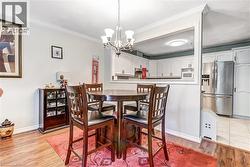Wood-finish flooring, crown molding, and a chandelier illuminate the dining area - 