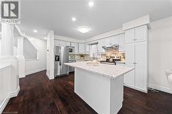 Kitchen featuring a center island with a light-toned countertop, white cabinetry, stainless steel appliances, and a tiled backsplash - 