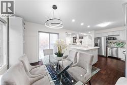 Open-concept dining area featuring a contemporary lighting fixture, wood-finish flooring, and white built-in cabinetry - 