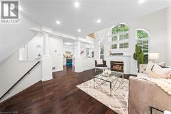 Recessed lighting, wood-finish flooring, white fireplace with mantel, arched windows with shutters, and architectural columns - 
