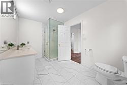 Bathroom featuring a glass-enclosed shower, white vanity with an undermount sink, light-toned countertop, and large format tile flooring - 