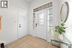 Entryway featuring a main door with decorative glass, two side panels with textured glass, a transom window, and square tile flooring - 