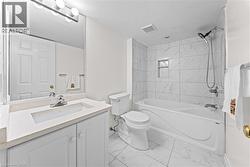 Bathroom featuring a vanity with an integrated sink, a large wall-mounted mirror, white shaker-style cabinetry, and a bathtub with a tiled surround - 