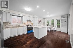 White cabinetry, wood-finish flooring, recessed lighting, central island with seating, and integrated shelving - 