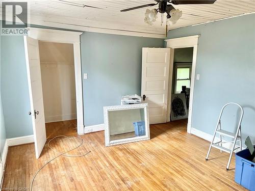 Bedroom  flooring with natural finish, white paneled doors, ceiling fan with light fixture, and painted walls - 128 Kent Street S, Simcoe, ON 