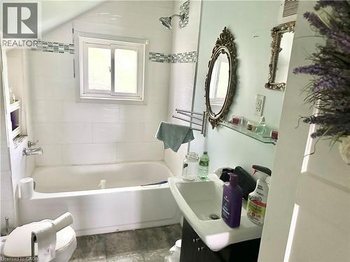 White tiled shower surround with accent band, built-in shower niche, chrome shower head, and a sliding window - 128 Kent Street S, Simcoe, ON 