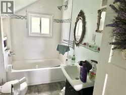 White tiled shower surround with accent band, built-in shower niche, chrome shower head, and a sliding window - 