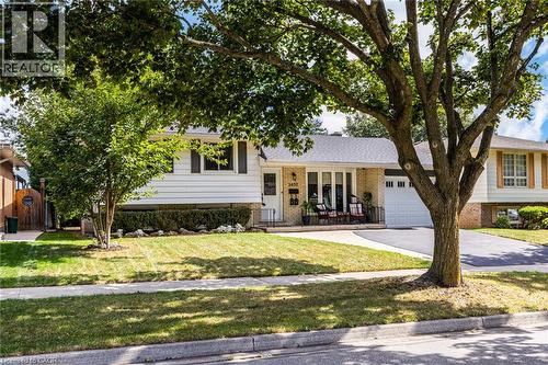 Exterior featuring light brick and white siding, an attached garage, a paved driveway, and a front porch with a white railing - 2037 Mountain Grove Avenue, Burlington, ON 
