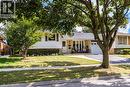 Exterior featuring light brick and white siding, an attached garage, a paved driveway, and a front porch with a white railing - 2037 Mountain Grove Avenue, Burlington, ON 