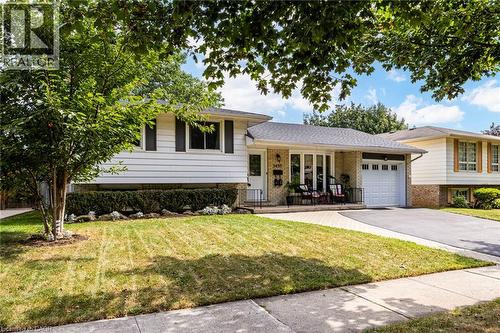 White siding exterior with brick accents, attached garage, paved driveway, and mature landscaping - 2037 Mountain Grove Avenue, Burlington, ON 
