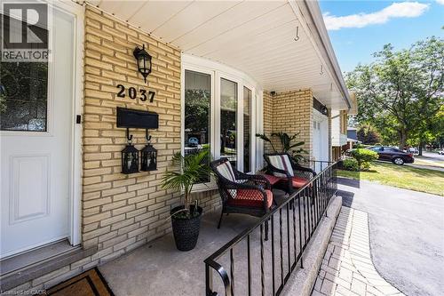Brick exterior with a covered front porch featuring a bay window, wrought iron railing, and concrete flooring - 2037 Mountain Grove Avenue, Burlington, ON 