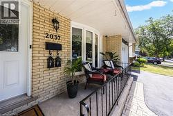 Brick exterior with a covered front porch featuring a bay window, wrought iron railing, and concrete flooring - 