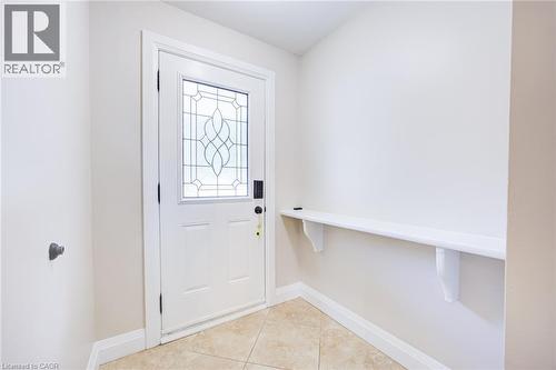 Entryway featuring a white door with decorative glass inserts, ceramic tile flooring, a built-in shelf, and neutral wall tones - 2037 Mountain Grove Avenue, Burlington, ON 