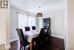 Dark wood-finish flooring, white wall paint, crown molding, and a drum pendant light fixture - 