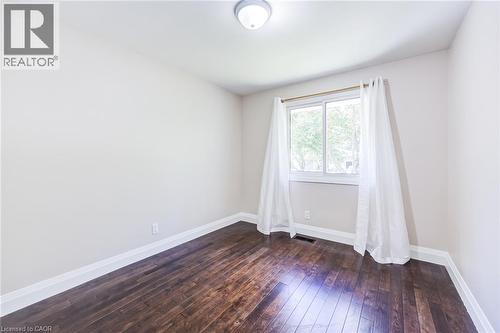 White painted walls with dark wood-finish flooring, white trim, and a ceiling-mounted light fixture - 2037 Mountain Grove Avenue, Burlington, ON 