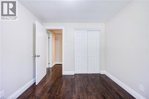 Wood-finish flooring with white baseboards, light neutral wall paint, and white paneled bi-fold closet doors - 2037 Mountain Grove Avenue, Burlington, ON 
