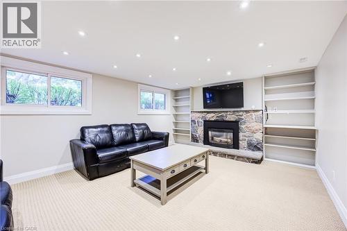 Stone-faced fireplace with a built-in hearth, flanked by integrated shelving units, recessed ceiling lighting, and wall-mounted television - 2037 Mountain Grove Avenue, Burlington, ON 