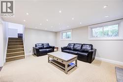 Recessed lighting throughout, two windows with white trim, and a carpeted staircase - 